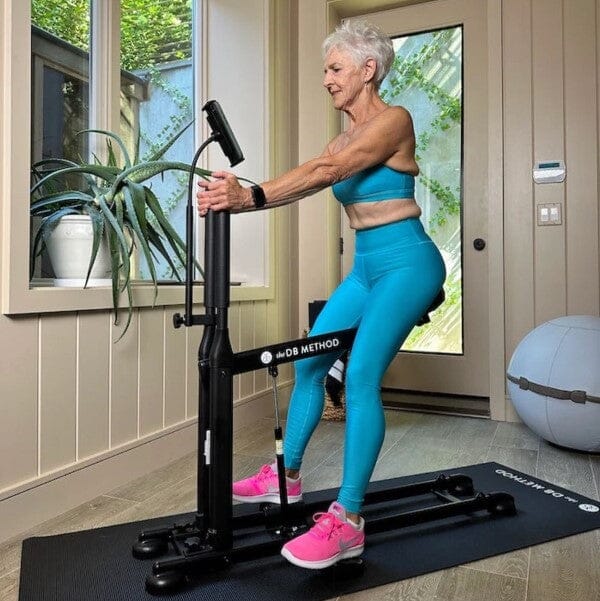 A woman in blue active wear using the DB Method machine.