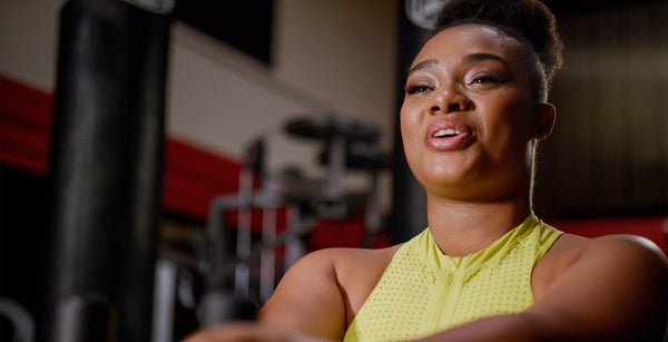 Smiling woman exercising in a home gym setting, focused and engaged during a mindful workout by The DB Method.