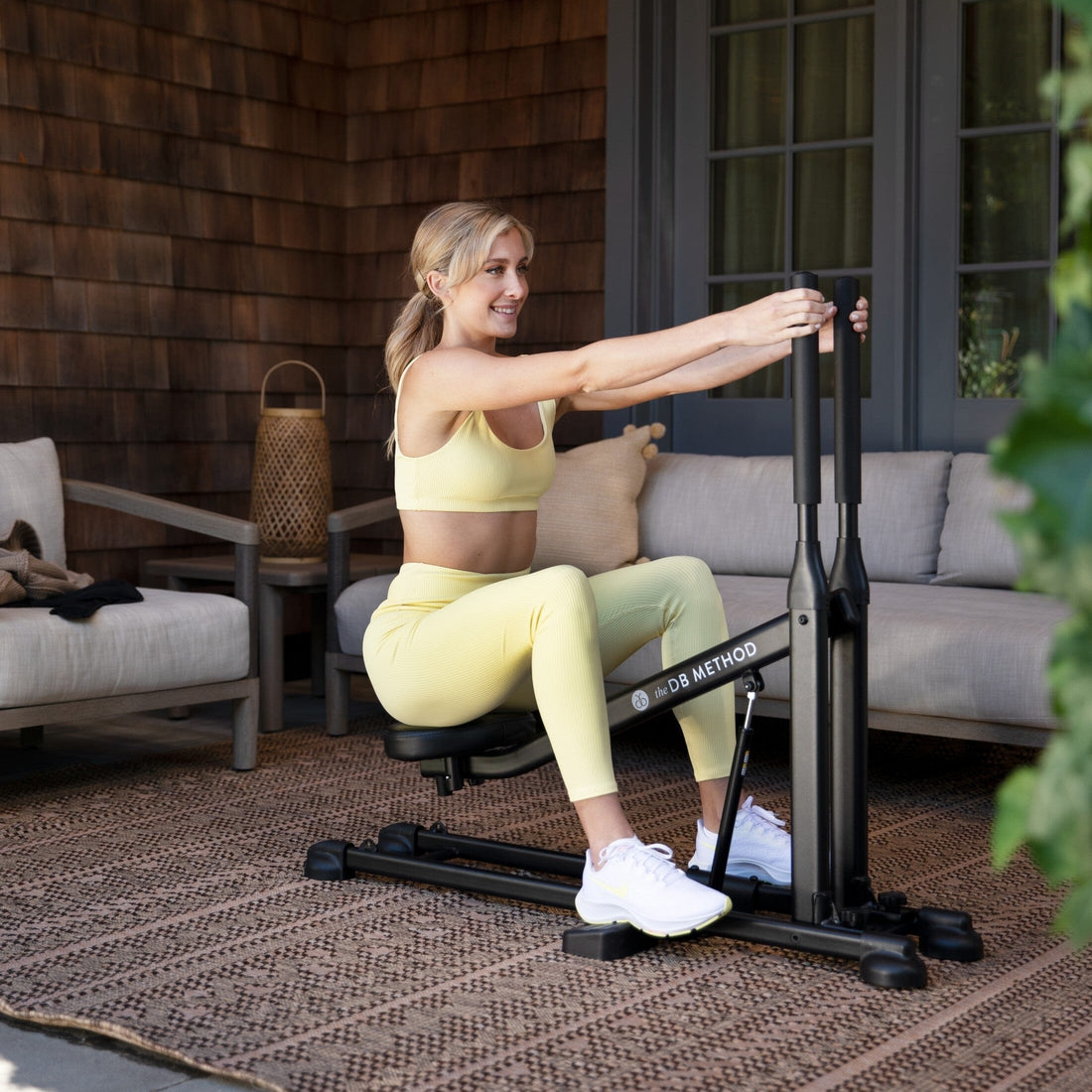 A woman works out on The DB Method Machine outdoors.