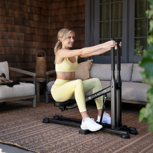 A woman works out on The DB Method Machine outdoors.